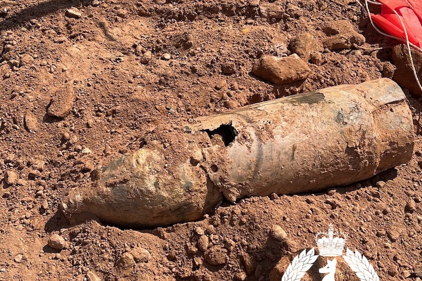 An old bomb is seen lying atop dirt at a construction site.