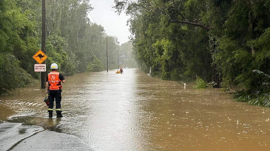 two sate emergency service volunteers on a flooded road with one on a rubber boat