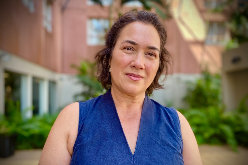 A woman standing in front of an apartment complex and smiling. 