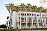 A grand looking building is surrounded by palm trees.