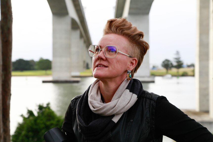 Jen Daine stands under two bridges and looks up into the distrance. 