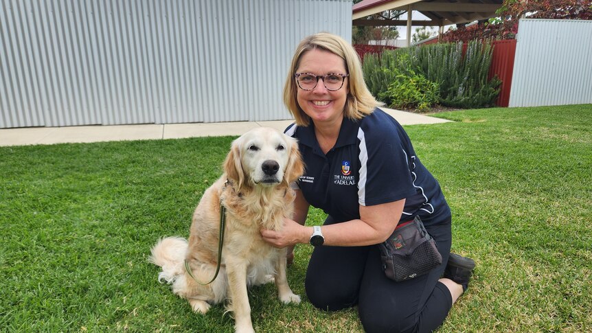 A blonde woman sits next to a middle aged white dog. 