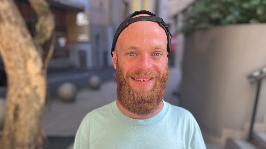 Tyler Byrnes wearing a black cap and green shirt smiling