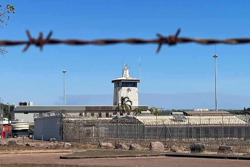 The exterior of the Don Dale Youth Detention Centre, with barbed wire in the foreground. 