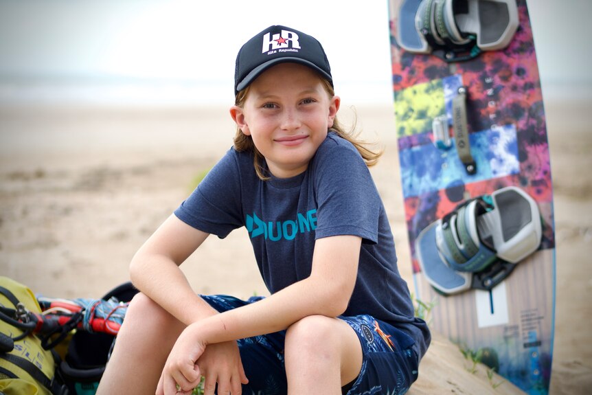 Fynn Goat sits on the beach with his kite surfing equipment.