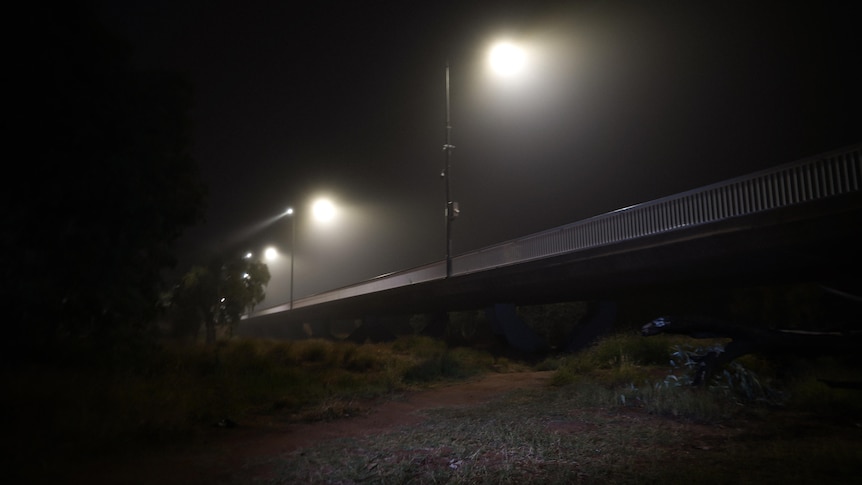 A bridge at night with street lamps turned on above it 