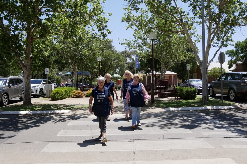 Four women crossing a pedestrian crossing in navy blue bibs