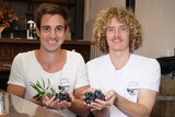 Dean Martellozo and Jared Smith hold handfuls of Illawarra plums with bottles of spirits in the foreground.