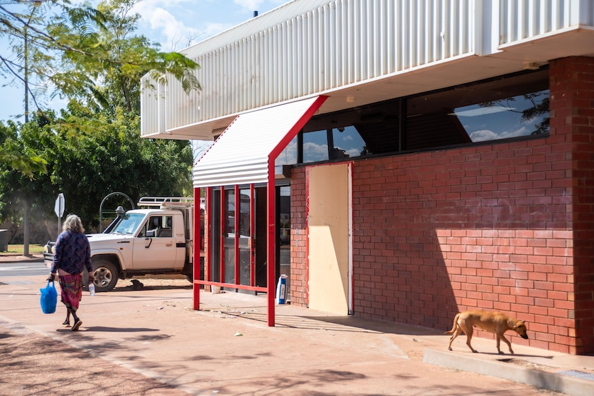 a woman walks past an abandoned bank