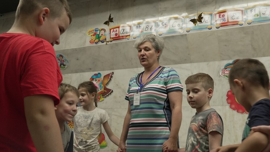 A group of kids holding hands with a teacher.