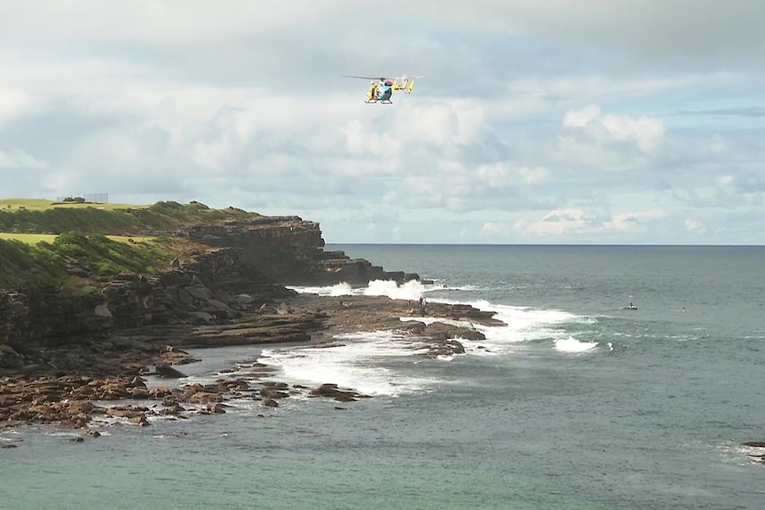 a search helicopter hovers over the ocean at little bay in sydney's south-east after two people drowned