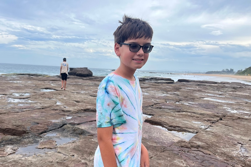 Riley standing on rocks near a beach.