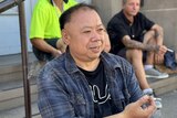 Ronald Liu sits on a step in Western Sydney with a cigarette in hand