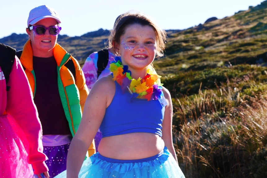 a girl smiles at the camera while walking in a blue tutu