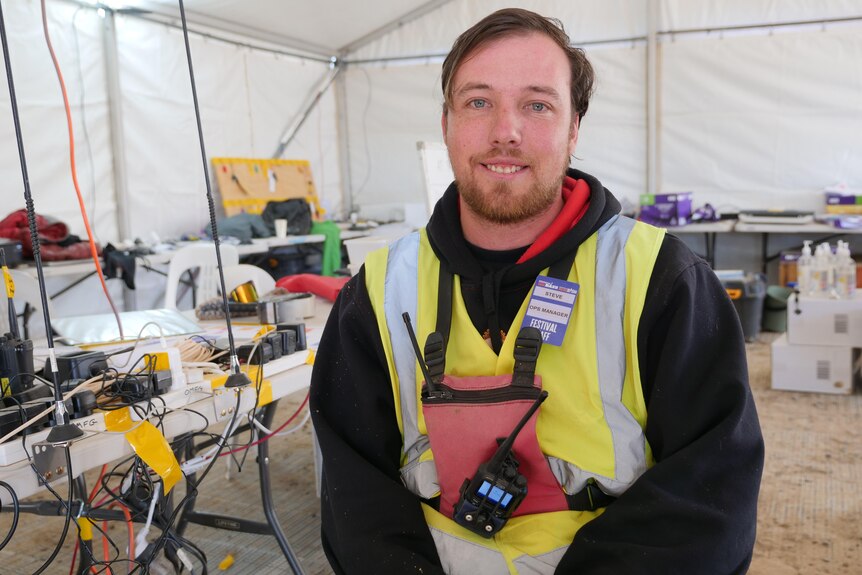 Steven Donovan sitting in the operations tent at the big red bash smiling at the camera. 