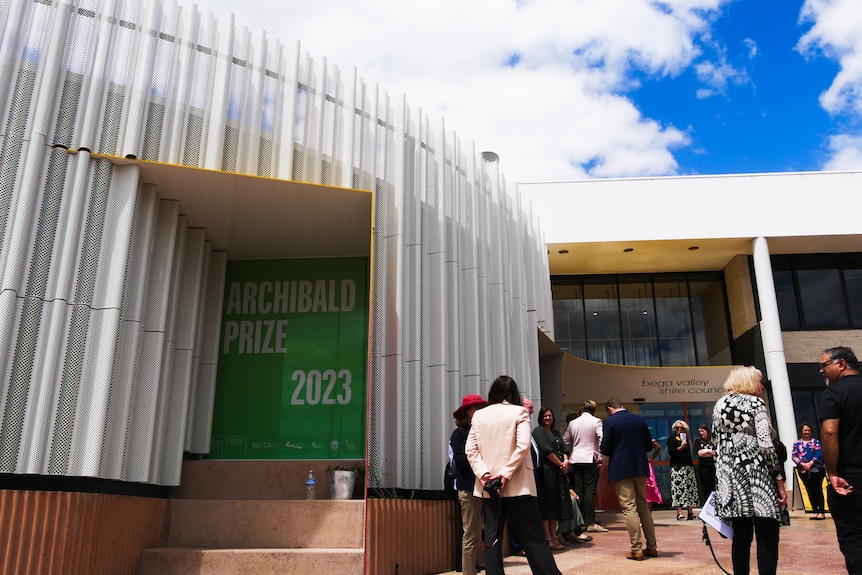 a group of people outside the gallery with tall walls and blue skies