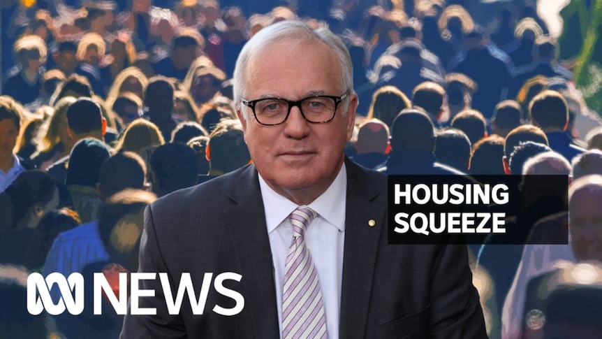 Housing Squeeze: A man with glasses looks at the camera with a backround of a significant amount of pedestrians.