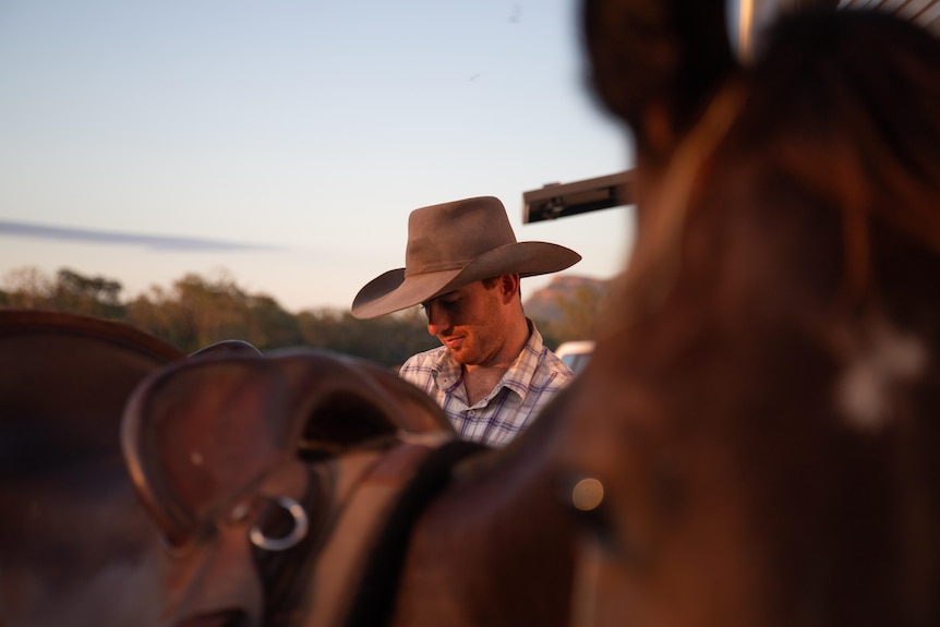 A man wearing an Akubra-style hat with horses.