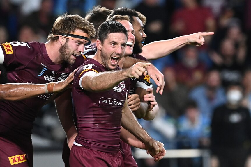 Ben Hunt points and shouts as his Queensland Maroons teammates celebrate with him during a State of Origin game.