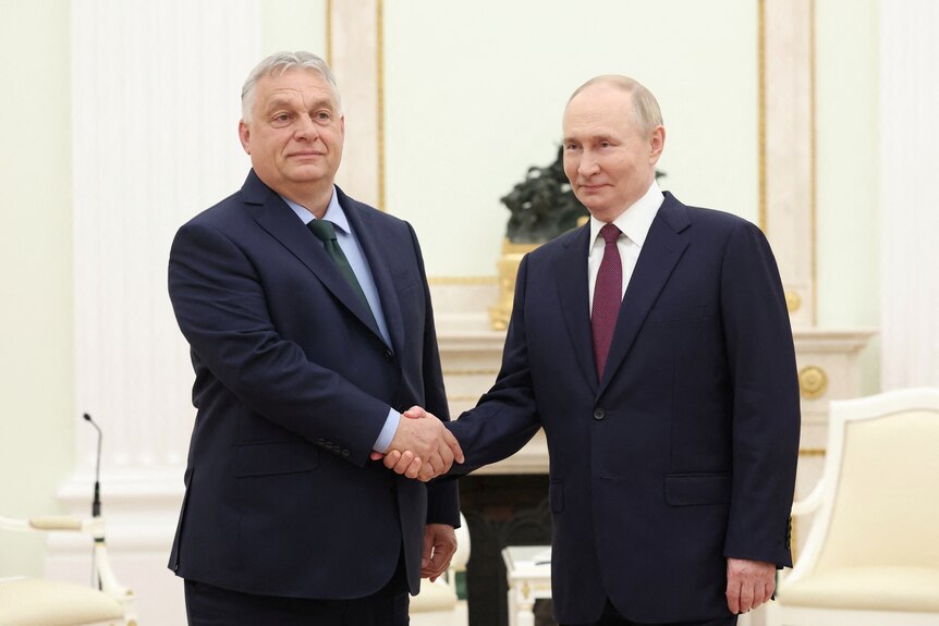 Viktor Oban and Vladimir Putin shake hands in a cream-coloured room.