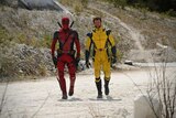 Comic book characters Deadpool and Wolverine walk towards the camera in full costume.