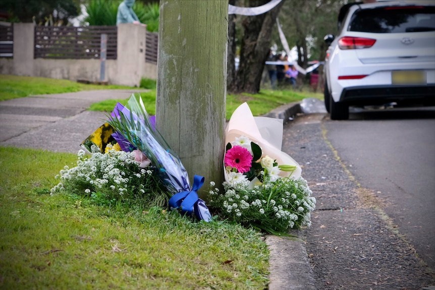 flowers on the side of a road at the scene of a fatal fire at lalor park