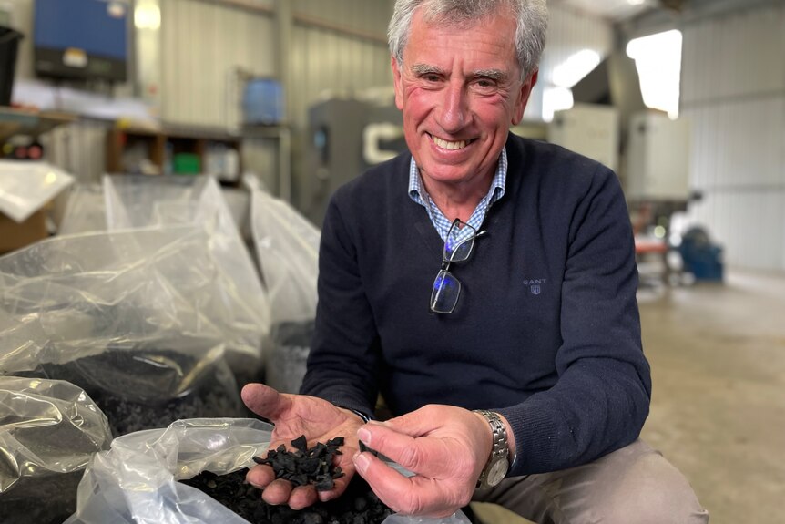 Photo of a man holding charcoal in his hand.