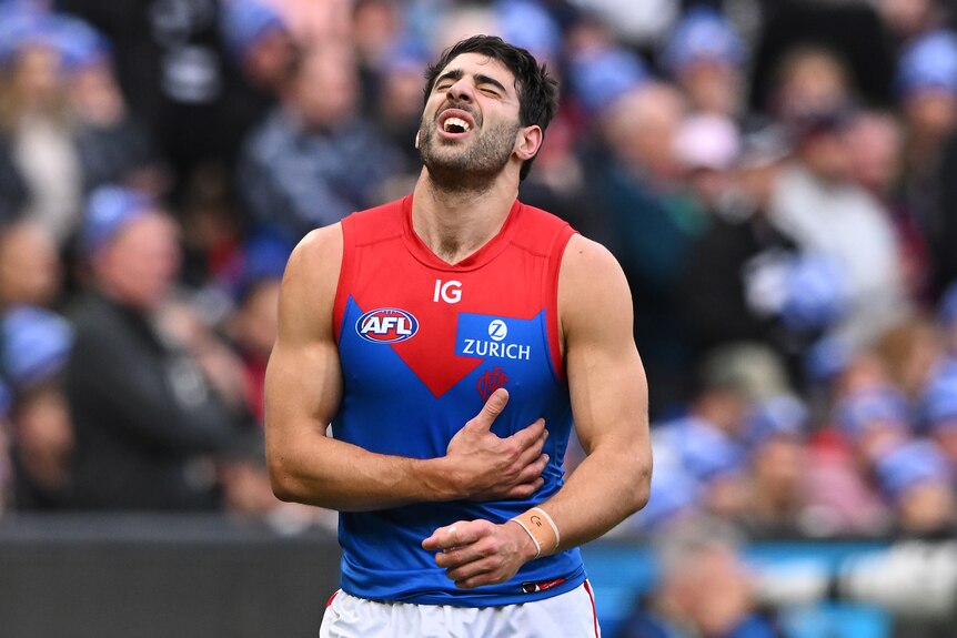 Christian Petracca of the Demons exiting the field, whincing in pain, holding his side