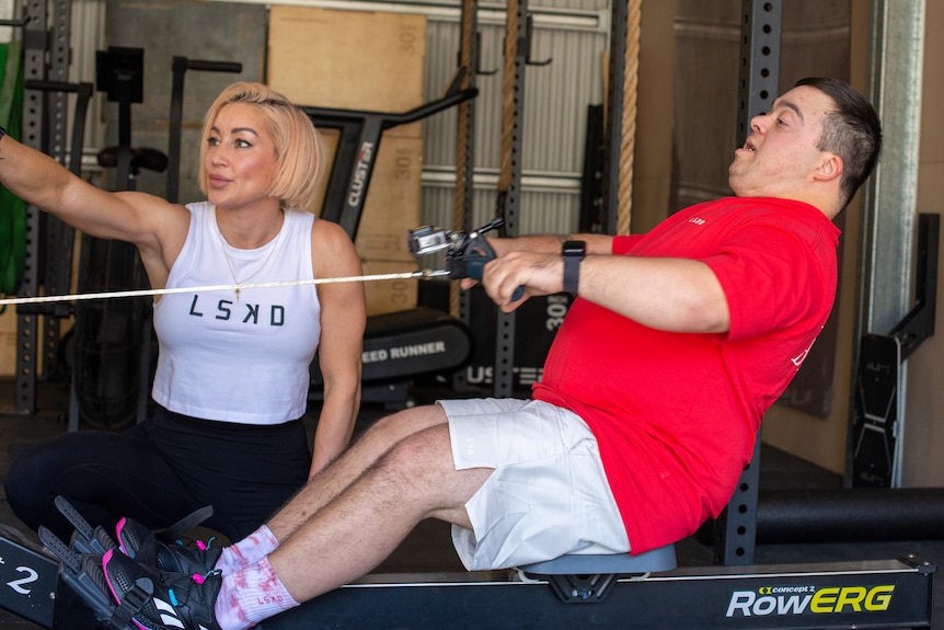 A young man exercises on a static rowing machine.