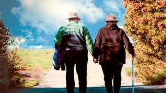 Older couple walking along a road hand-in-hand