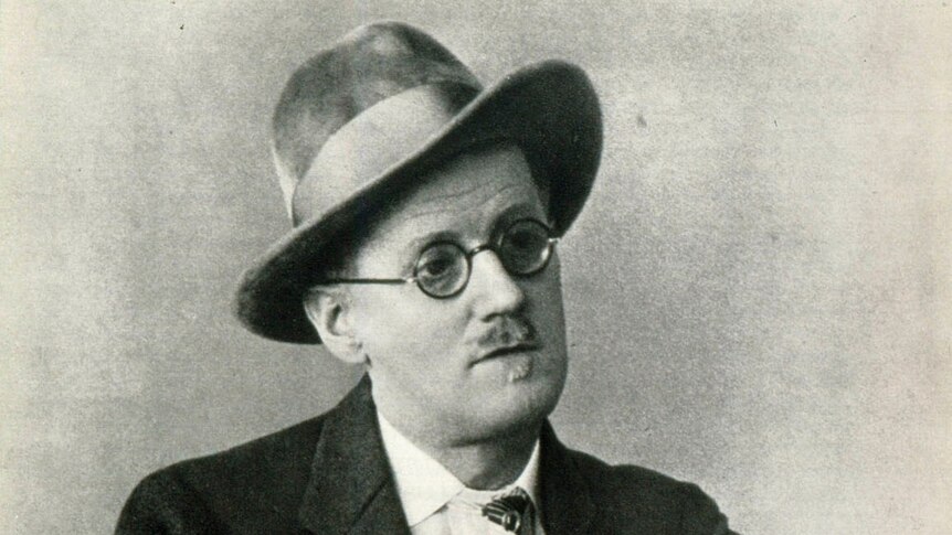 A black and white image of a man wearing a hat, glasses and a suit and tie.