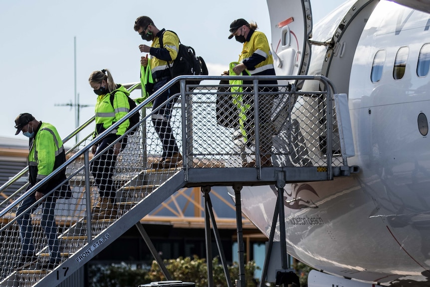 people in hi vis getting off a plane