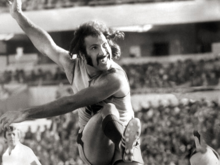 A photo showing a man kicking an AFL football.