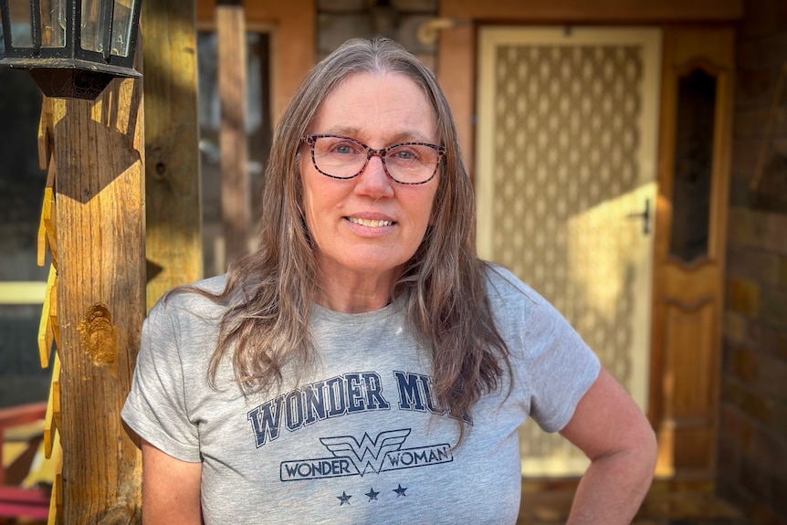 A woman wearing glasses looks right at the camera. 