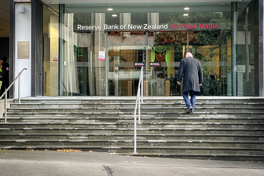 A man in an overcoat walks up the stairs to the Reserve Bank of New Zealand's headquarters in Wellington.