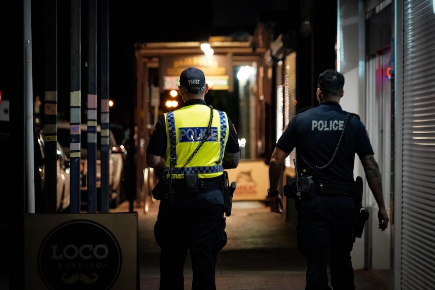 two police officers walking down a deserted street from behind