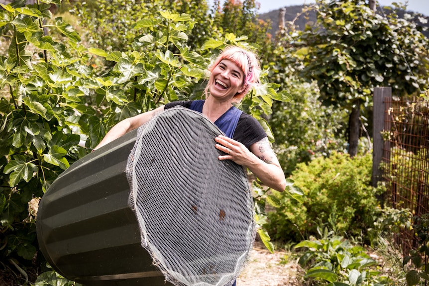 Hannah Moloney holding a compost bin in the garden 
