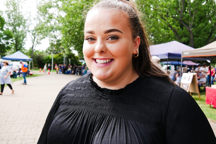 A woman smiles at the camera with a crowd in the background