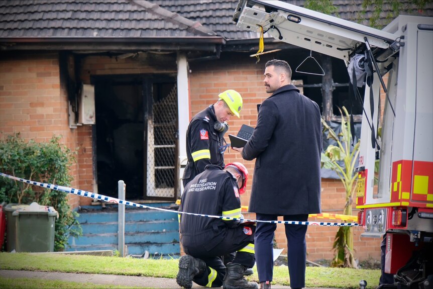 Police tape cover the driveway of a burnt out home.