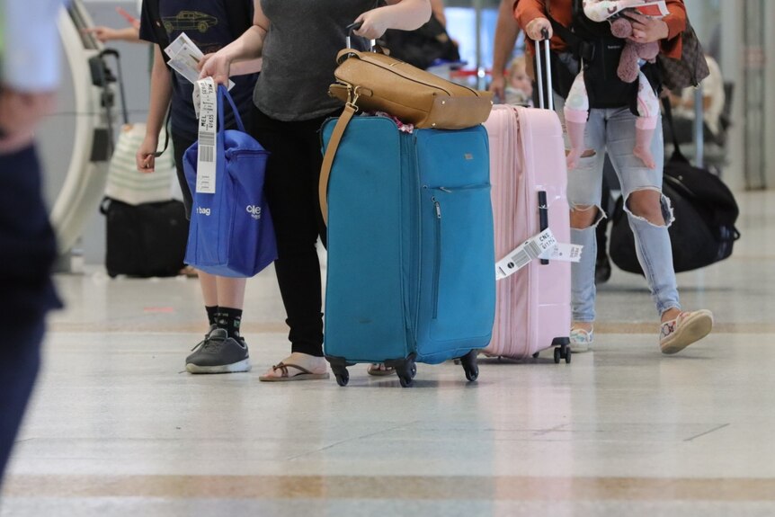 An unidentified person rolls a suitcase and carries a coles bag through the Brisbane Airport.