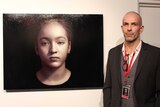 Man standing next to painting of young girl