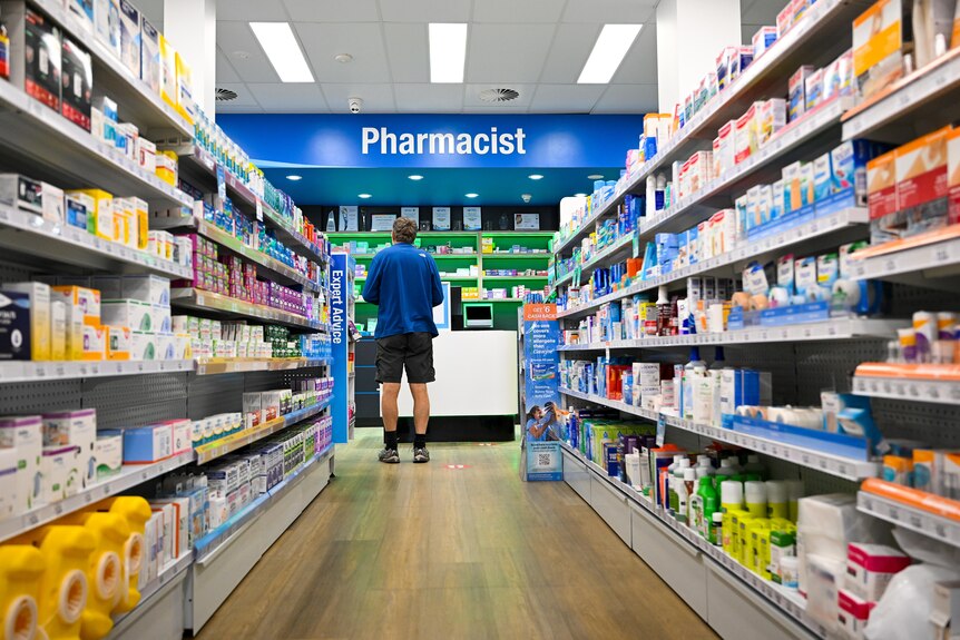 a male customer stands waiting at a pharmacy counter