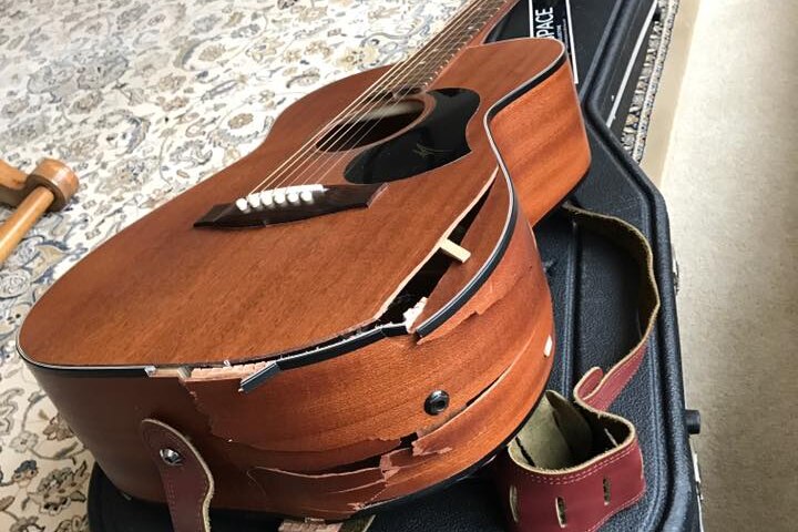 photo of a guitar with its body broken on a black hard case