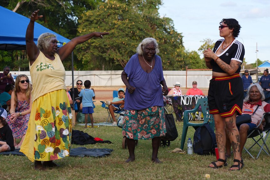 Two elderly Indigenous woman and another younger woman dance in a park