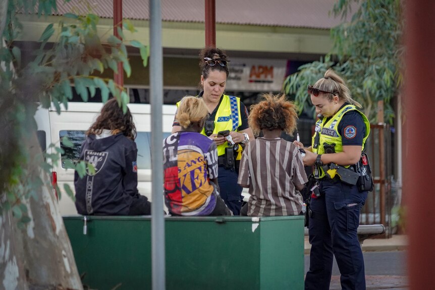 Two police officers talk to three kids in the Alice Springs CBD.