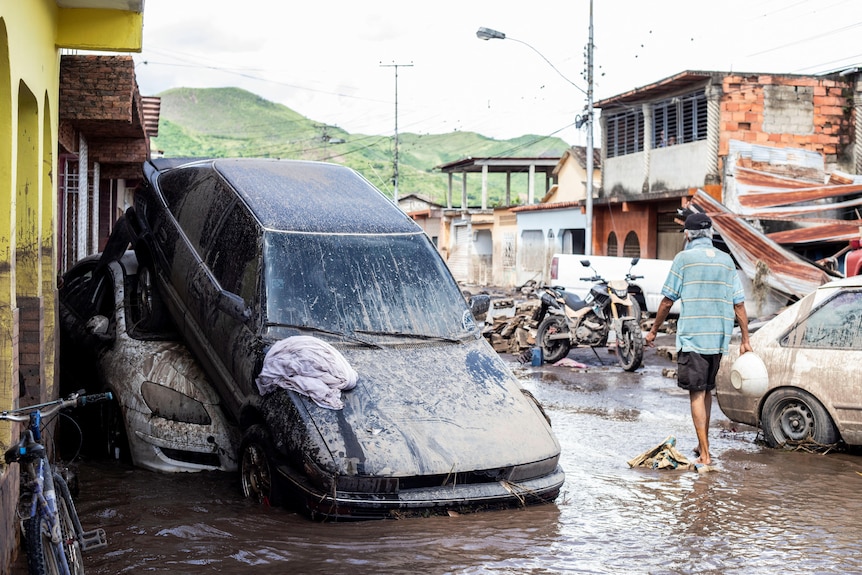 Car on top of another vehicle in flood water. 