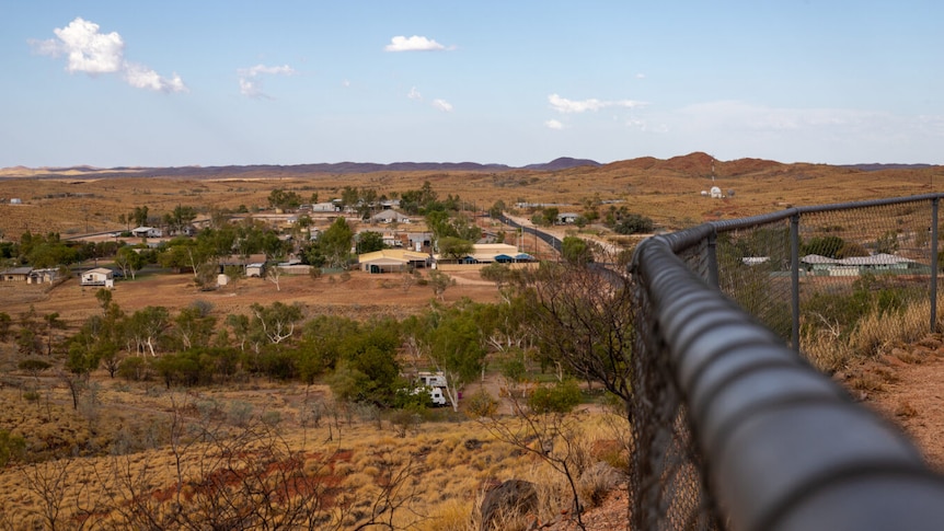 A small townsite in the desert with a fence in the foreground.