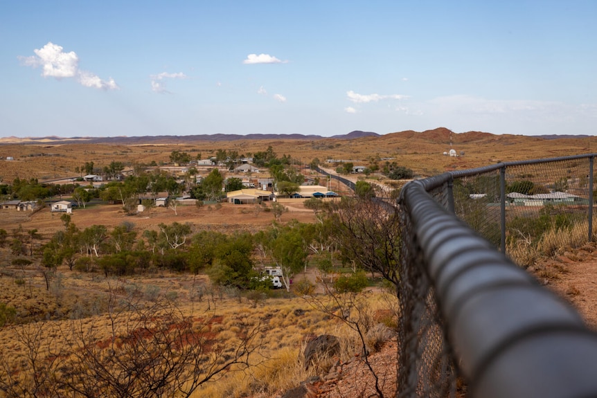 A small townsite in the desert with a fence in the foreground.