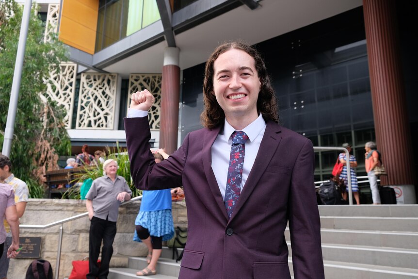 A young man in a suit outside court.