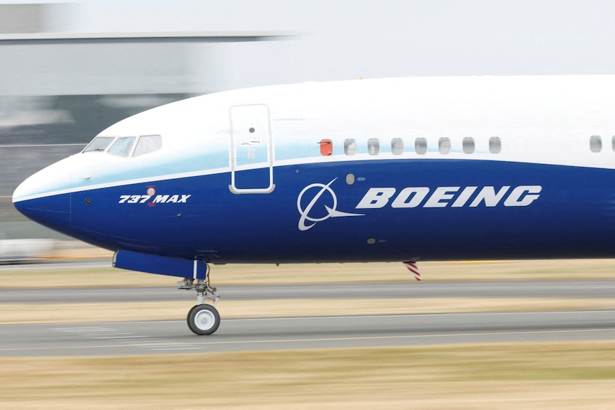 A white and blue plane with the word 'BOEING' and the markings '737 MAX' written on its side.